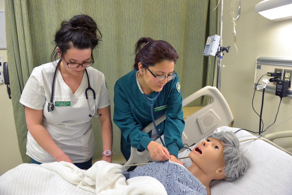 Two health students work with a patient simulator